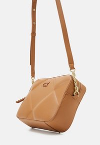 Brązowa torba na ramię z geometrycznym pikowanym wzorem, z złotym zamkiem błyskawicznym i okuciami, regulowanym paskiem oraz wytłoczonym logo.