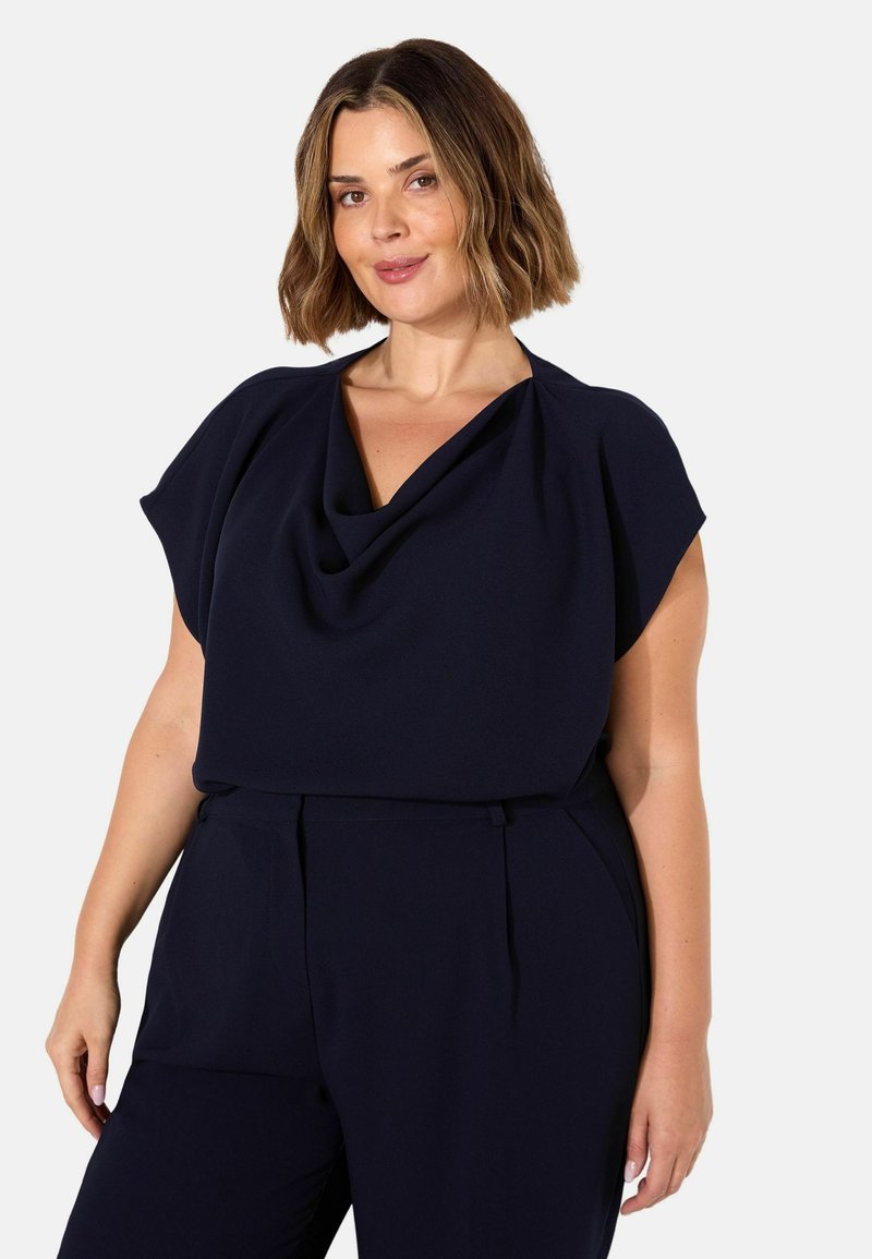 Top blu navy con scollo drappeggiato e maniche corte. Il tessuto è liscio, con una vestibilità rilassata. Abbinato a pantaloni coordinati.