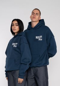 Navy blue hoodies with a front pocket and “MULTI PLY” text. Made from a soft fabric with a relaxed fit and ribbed cuffs.