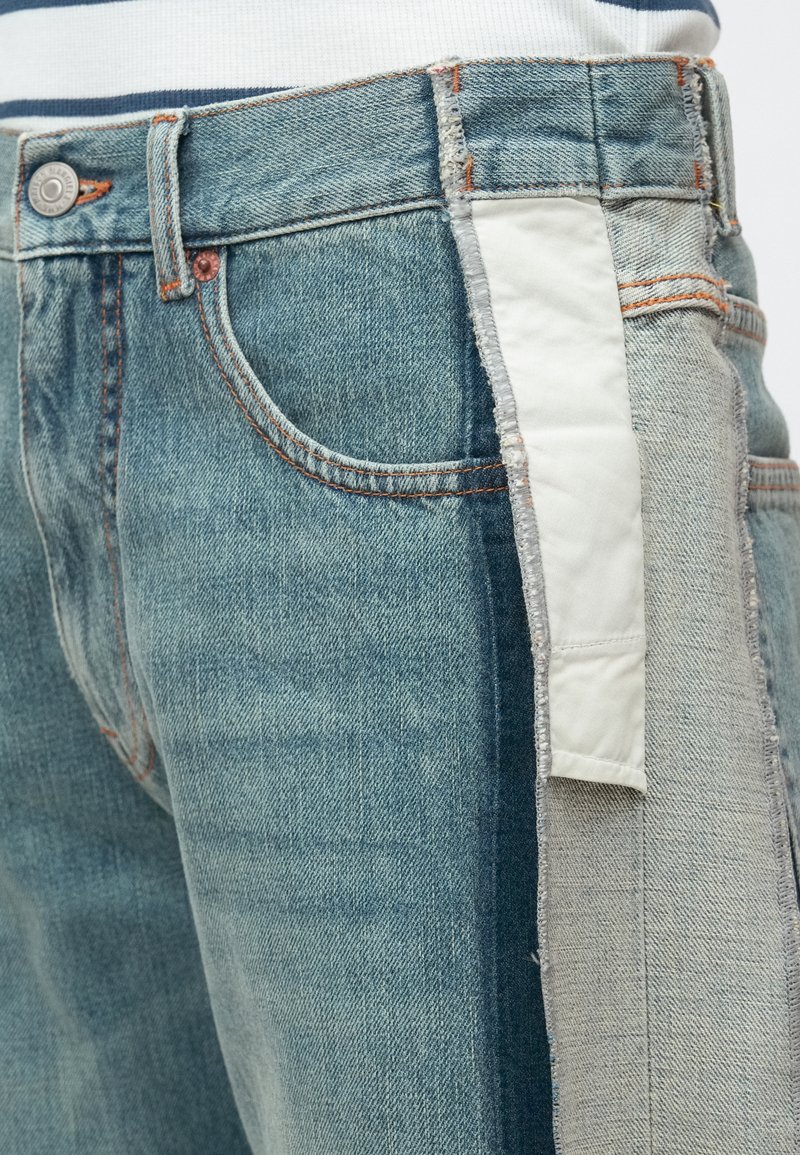 Jeans i denim i olika blå nyanser med en vit tyguppvikning. Har den traditionella femfickdesignen och stitchdetaljer.