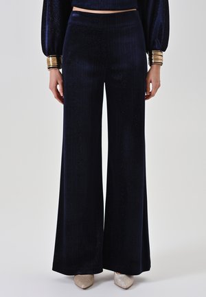 Pantaloni navy a gamba larga in morbido materiale con una sottile lucentezza, caratterizzati da texture a coste verticali e una vita alta per un fit moderno.