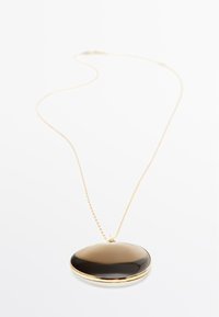 Collana in oro con ciondolo ovale nero caratterizzato da una superficie liscia e una finitura lucida. Il ciondolo è bordato con una cornice dorata.