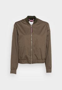 Giacca bomber verde oliva con chiusura a zip, colletto e polsini a coste e vita elastica. Presenta una lucentezza sottile e senza motivi visibili.