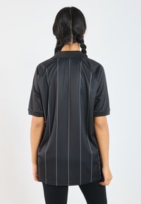 Zwarte sportshirt met kraag, voorzien van verticale witte strepen. Gemaakt van gladde stof met korte mouwen en een relaxte pasvorm.