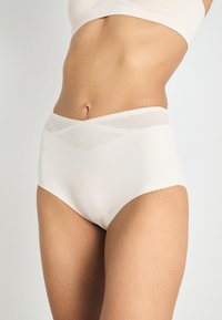 High-waisted, cream-colored underwear with a smooth fabric and textured mesh waistband featuring a chevron pattern.