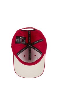 Red baseball cap with a cream front brim, interior brand label, and black accents. Features ventilation holes and an adjustable strap.