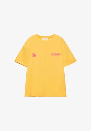 Sárga rövid ujjú póló rózsaszín nap grafikával és a "SUN-CHASING LOS ANGELES, CA" felirattal az elülső bal oldalon.