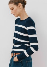 Maglioncino a righe blu navy e bianche con maniche lunghe realizzato in cotone. Presenta un collo rotondo e un design aderente, abbinato a jeans blu e una cintura.