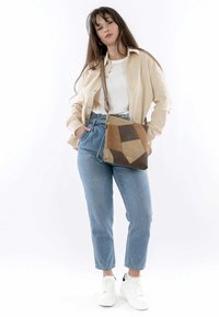 Geometric patchwork handbag in beige, brown, and dark brown leather. Features a detachable strap and textured surface.