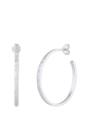 Paire de boucles d'oreilles créoles texturées en argent avec des bords plats, l'une montrée de face et l'autre de côté avec un fermoir papillon.