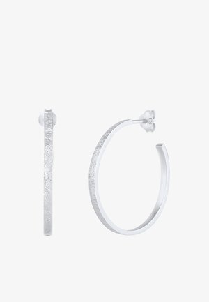 Paire de boucles d'oreilles créoles texturées en argent avec des bords plats, l'une montrée de face et l'autre de côté avec un fermoir papillon.