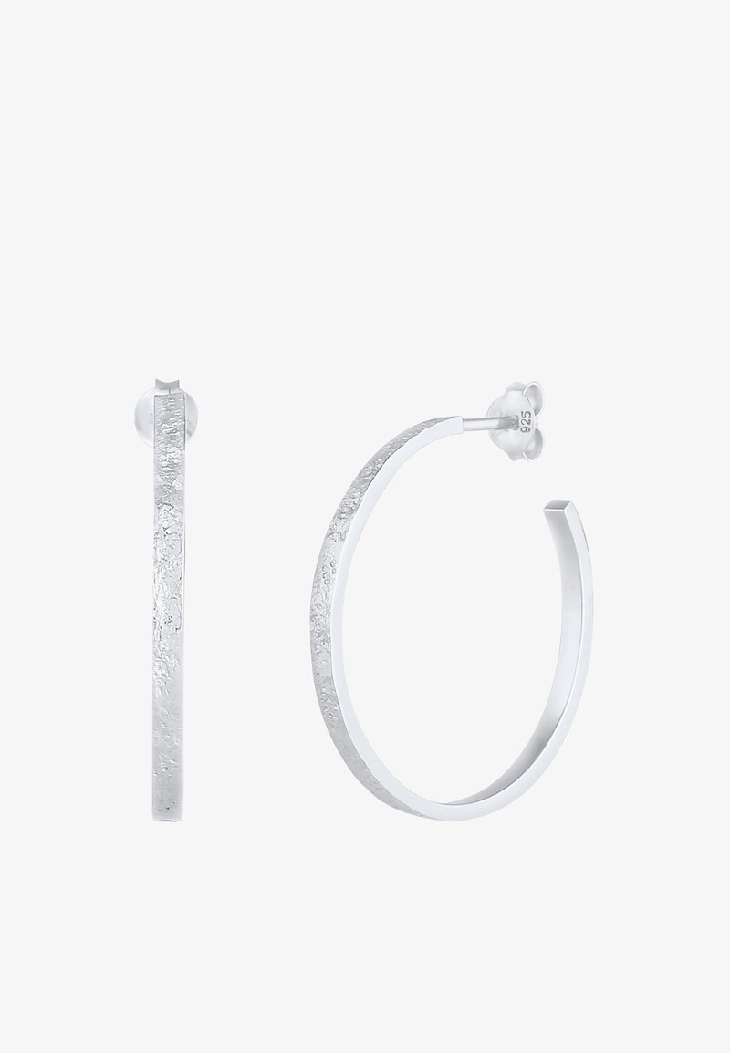 Paire de boucles d'oreilles créoles texturées en argent avec des bords plats, l'une montrée de face et l'autre de côté avec un fermoir papillon.