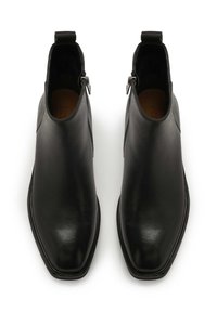 Mustad mustad nahast pahkluu saapad, millel on stiilne disain, terav tipmine varvas ja külgmine tõmblukk. Omab silmust tõmbele, et hõlbustada jalga panemist.