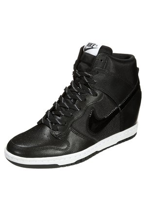 Czarne wysokie sneakersy Nike z teksturowaną skórą, białą podeszwą, czarnymi sznurówkami w białe kropki oraz błyszczącym czarnym logo Nike swoosh po boku.