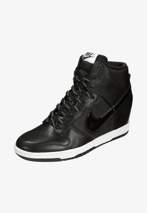 Czarne wysokie sneakersy Nike z teksturowaną skórą, białą podeszwą, czarnymi sznurówkami w białe kropki oraz błyszczącym czarnym logo Nike swoosh po boku.