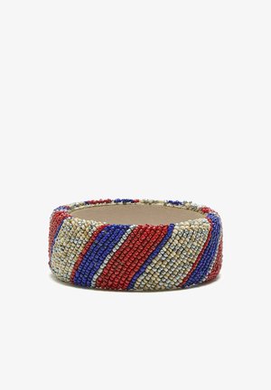 Braccialetto largo di perline con strisce diagonali in perline rosse, blu, crema e argento su una fascia interna color sabbia.
