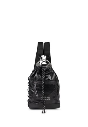 Mochila negra con cordón, bolsillo delantero con cremallera, correas anchas para los hombros y texto reflectante en la parte frontal, mostrada sobre un fondo blanco.