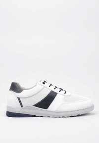 Baskets de sport blanches avec un design en maille perforée, accents noirs sur les côtés et une semelle grise. Dispose de six œillets et de lacets.