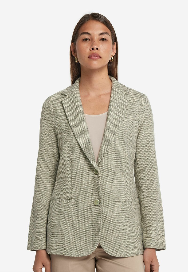 Ljusgrön texturerad blazer med en knapp, snedskurna klackar och två framfickor, tillverkad av vävt tyg.