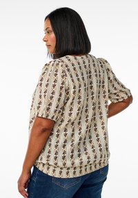 Short-sleeve blouse in cream with vertical stripes, floral patterns in dark purple and golden hues, textured fabric, and a relaxed fit.