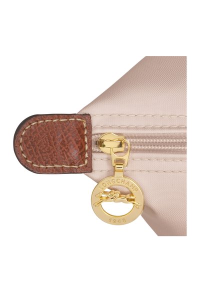 Beige nylon pouch with a brown leather accent, featuring a gold zipper pull and a round logo tag with "LONGCHAMP 1948" inscribed.