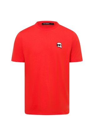 Rode katoenen T-shirt met een ronde hals. Bevat een klein zwart-wit grafisch logo op de linkerkant van de borst. Korte mouwen en reguliere pasvorm.