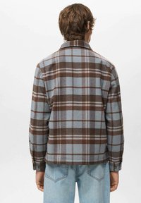 Camisa de cuadros con patrón de cuadros marrón y azul claro, cuello clásico, mangas largas y puños con botones. Hecha de tela suave, diseño de corte relajado.