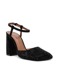 Scarpa nera con tacco a punta, caratterizzata da piccole borchie lucide. Dotata di una cinghia alla caviglia e di un tacco a blocco per maggiore stabilità.
