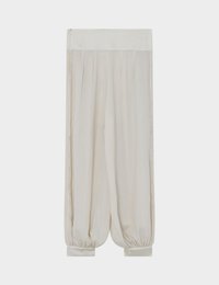 Pantalon ample de couleur crème avec poignets et ceinture élastiques, présenté à plat sur un fond blanc.