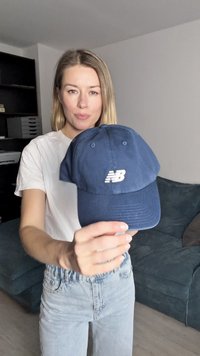 Casquette de baseball en coton bleu marine avec un logo "NB" blanc sur le devant, avec des œillets en métal pour la ventilation et une visière incurvée.