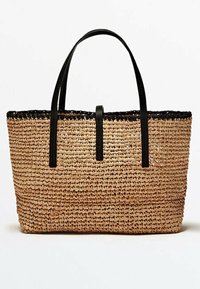 Sac cabas tissé en paille avec une forme rectangulaire, de couleur beige naturelle, bord supérieur noir et deux bretelles d'épaule noires. Surface texturée.