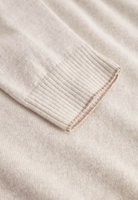 Hellbeige Pulloverärmel aus weicher, feiner Strickware. Besitzt eine gerippte Textur und einen kontrastierenden braunen Faden entlang des Saums.