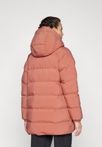 Pufová bunda v tlmených koralových farbách, s kapucňou, prešívaným dizajnom a elastickými manžetami. Hladký, ľahký materiál s voľným strihom.