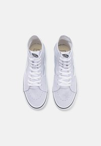Um par de ténis de cano alto Vans lilás claro com atacadores brancos e pormenores em preto, vistos de cima sobre um fundo branco.