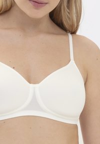 Soutien-gorge blanc, sans couture, avec des bonnets triangulaires, des bretelles ajustables et une texture lisse. Conçu pour le confort et un ajustement subtil.