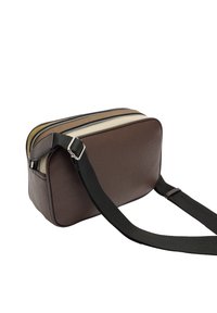 Brązowa skórzana torba na ramię z dwoma zapinanymi na zamek przegrodami, o teksturowanym wykończeniu i czarnym regulowanym pasku. Posiada kremowe i brązowe akcenty.
