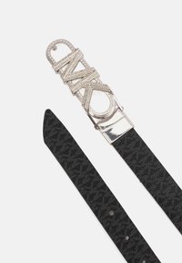 Cintura in tessuto nero con fibbia metallica decorata con pietre trasparenti, che mostra le lettere "MK" in un design stilizzato.