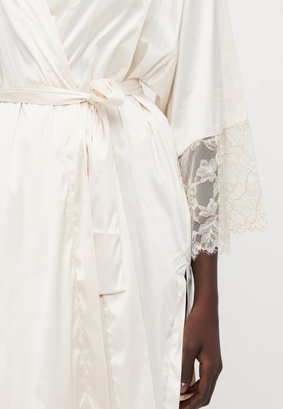Accappatoio in satin bianco sporco con cintura, caratterizzato da dettagli in pizzo sulle maniche e una texture liscia. Leggera lucentezza ed elegante design.