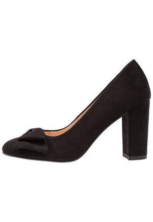 Czarna zamszowa szpilka z okrągłym noskiem i dekoracyjną kokardą na wierzchu buta. Obcas ma kształt bloku i jest teksturowany, co zapewnia stabilność.