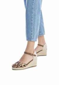 Sandalias de cuña con estampado de leopardo, suela de yute, tira en el tobillo beige y parte superior de tela suave. El diseño presenta una punta redondeada y acentos texturizados.
