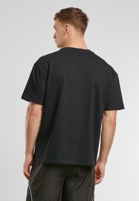 Svart bomull T-skjorte med avslappet passform, rund hals, og korte ermer. Stoffet er glatt med et minimalistisk design og ingen synlige logoer.