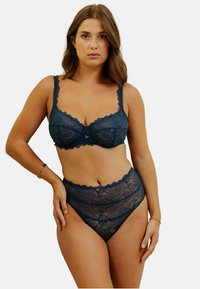 Ensemble en dentelle comprenant un soutien-gorge et une culotte taille haute de couleur bleu foncé. Présente des motifs floraux, des bords festonnés et un petit accent doré central sur le soutien-gorge.