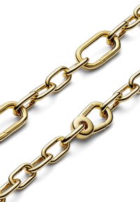 Cadena chapada en oro con eslabones ovalados y circulares alargados y alternados. Detalle notable en el cierre con grabado de la marca y textura suave.
