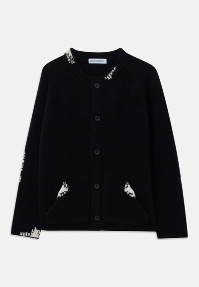 Juodas mygtukų kardiganas su apvalia kaklo iškirpte, priekinėmis kišenėmis ir baltomis raštuotomis detalėmis ant apykaklės, rankovių ir kišenžių.