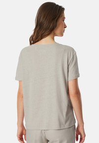 Světle šedé tričko s krátkým rukávem vyrobené z měkké tkaniny, s volným střihem a kulatým výstřihem. Zadní pohled ukazuje čisté linie.