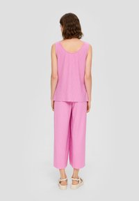 Roze mouwloze top en bijpassende wijde broek van textuurstof. De outfit heeft een ronde halslijn en een losse fit.