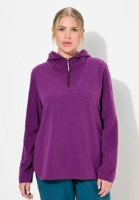 Sudadera de forro polar morada con cuello alto y media cremallera. Manga larga, corte relajado, textura suave y un diseño sencillo.