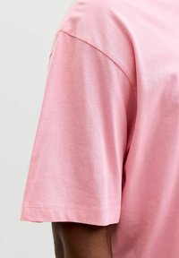 Heleroosa lühikeste varrukatega T-särk, millel on lõõgastav lõige. Pehme puuvillane materjal, lihtne disain, ümar kaelus ja õmmeldud äär.