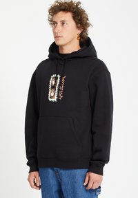 Zwarte hoodie met een grafisch ontwerp in groen, oranje en bruin. Gemaakt van een zacht materiaal met een kangoeroezak en een capuchon met trekkoord.