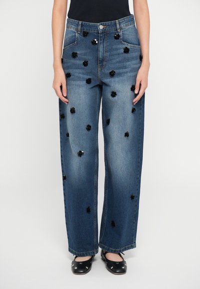 Jean en denim à jambes larges avec un lavage bleu clair et des embellissements en sequins noirs en forme de fleurs dispersés sur les poches avant et arrière.